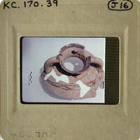 Broken clay pot with visible cracks and missing pieces, displayed on a white surface.