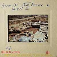 This is a photograph of an archaeological site with stone ruins and a dirt road, taken from a high angle perspective.