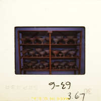 Row of dark brown vases on shelves.