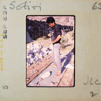 Man standing on a pile of rocks with cloth bags of pottery sherds.