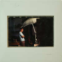 Man standing under an umbrella with his arms crossed.