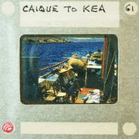 A vintage photo of a man and woman sitting on the deck of a boat with water in the background.