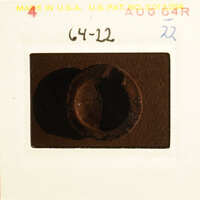 A close-up photograph of an object with a worn surface, possibly metal, on a dark background.