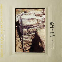 This photo shows a stone wall with a hose running through it, taken from an angle that emphasizes the texture and structure of the stones.