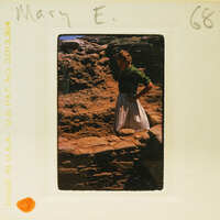 A vintage photo of a young girl standing on stone ruins.