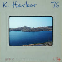 A vintage photograph of a serene harbor with calm waters and distant mountains.